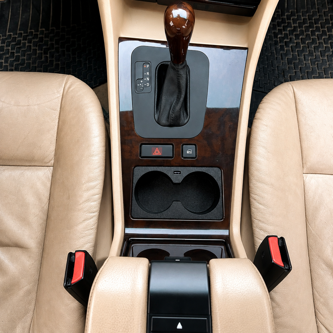 Car BMW E38 interior with beige leather seats and a center console featuring a gear shift and cup holders.