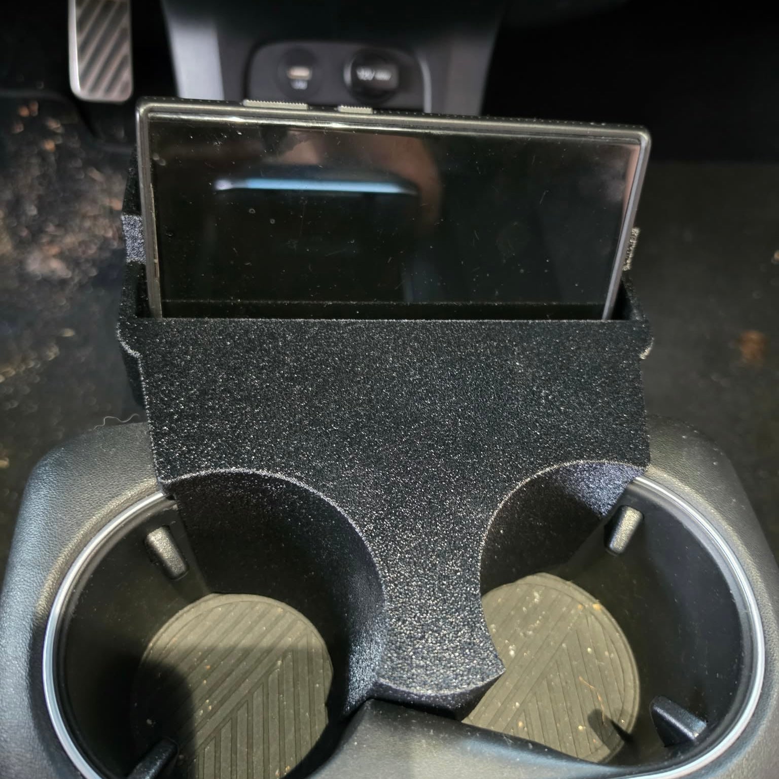 Angled view of Hyundai Ioniq 5 cup holder organizer with phone lying flat in landscape mode next to storage tray